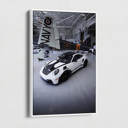 Vertical canvas art featuring a white Porsche 911 GT3RS with black stripes in a hangar setting Wall Art.