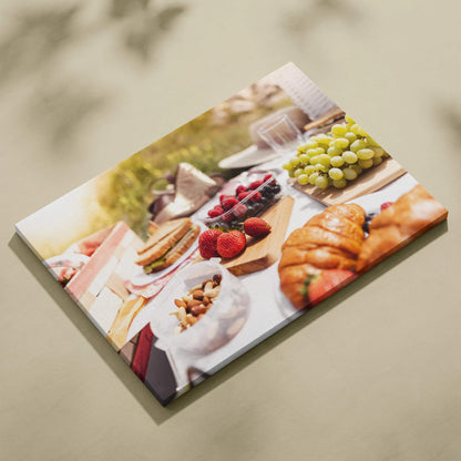 Canvas wall art featuring fresh strawberries, green grapes, croissants, and pastries on a rustic lunch table.