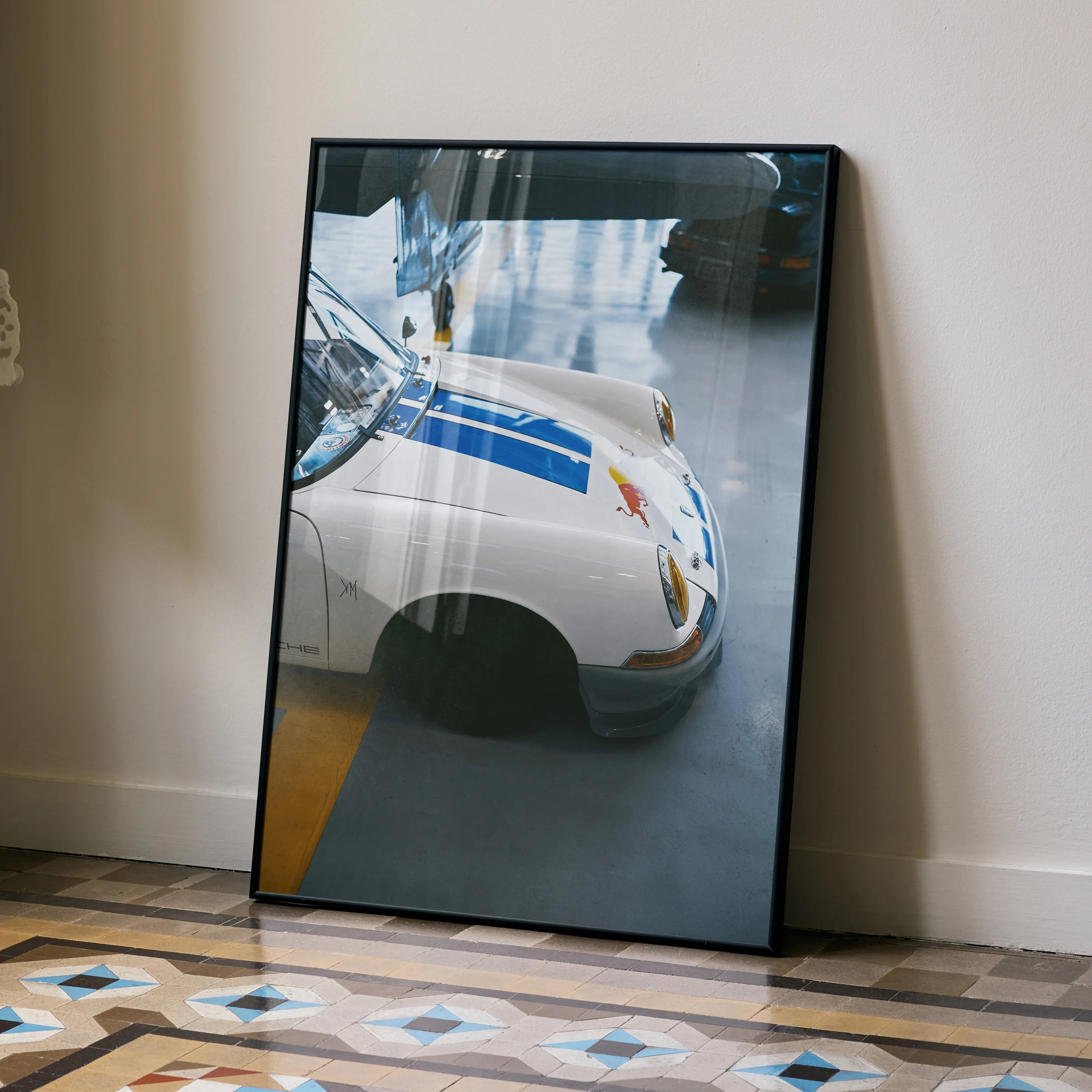 Porsche 911 Classic high resolution poster featuring white vintage car with blue racing stripes leaning against beige wall.