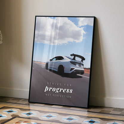 Poster wall art featuring a white Subaru WRX STI on a road under a blue sky with clouds and the quote "Strive for progress.
