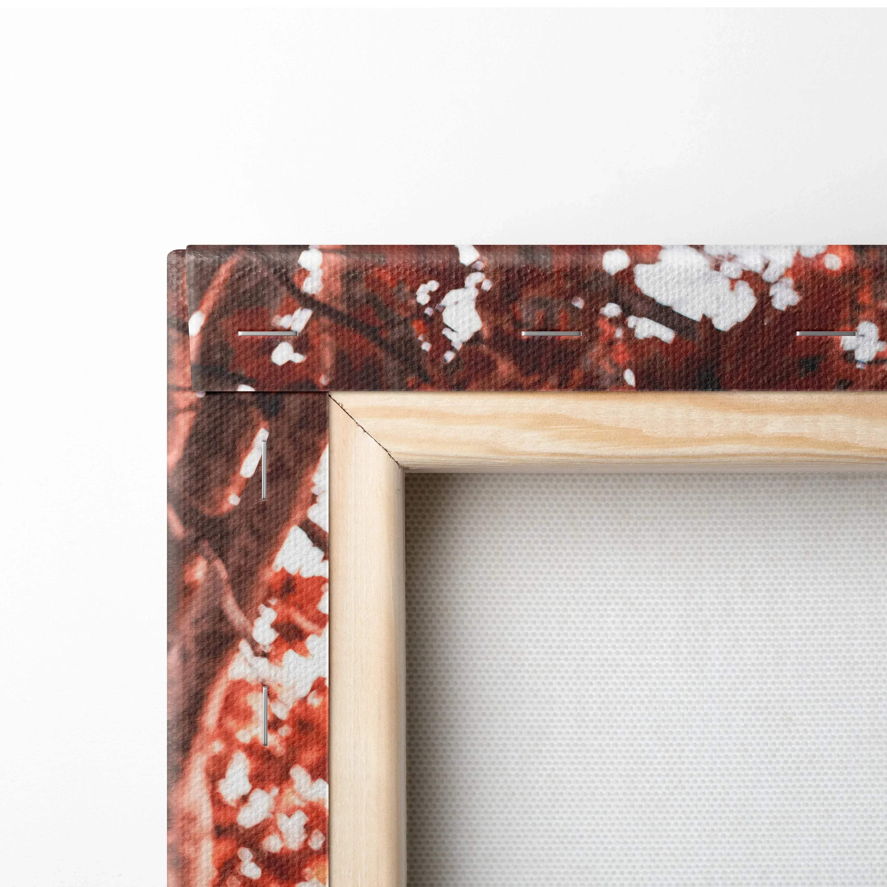 Close-up of wooden frame corner with red, white splattered canvas wall art texture.