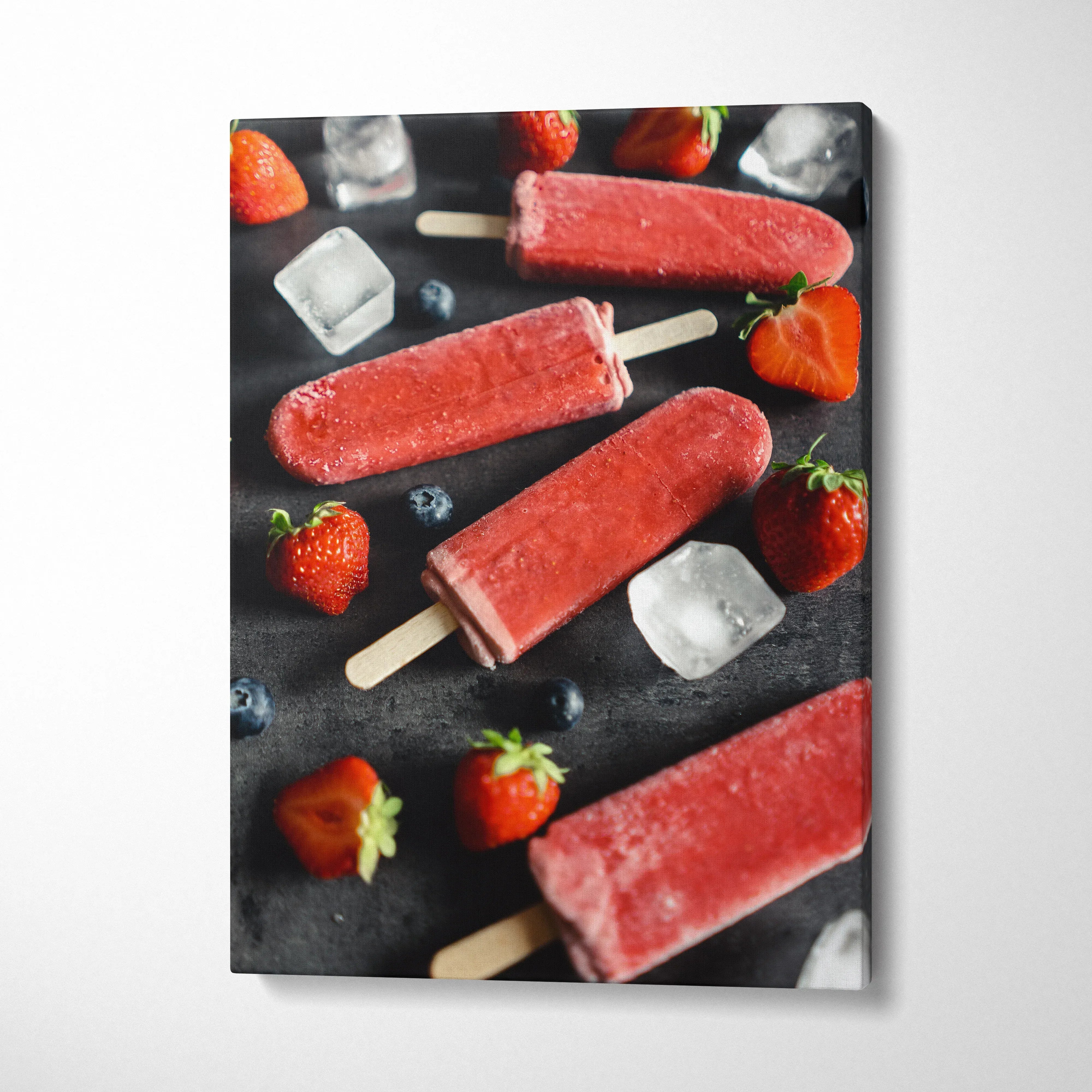 Canvas wall art featuring vibrant red strawberry popsicles with fresh strawberries and ice cubes on black background decor.