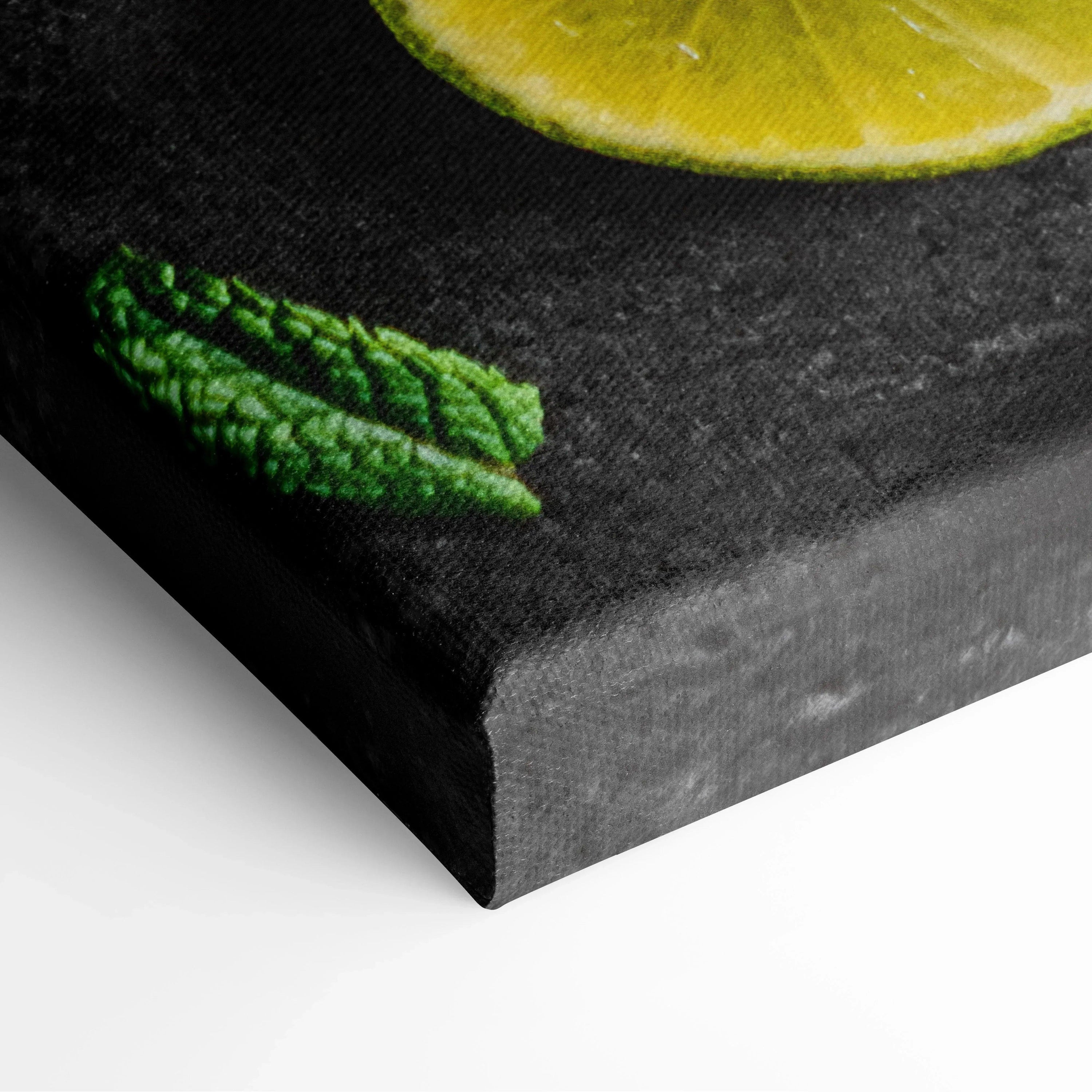 Close-up of black canvas wall art corner featuring a vivid green mint leaf and a yellow lime slice edge.