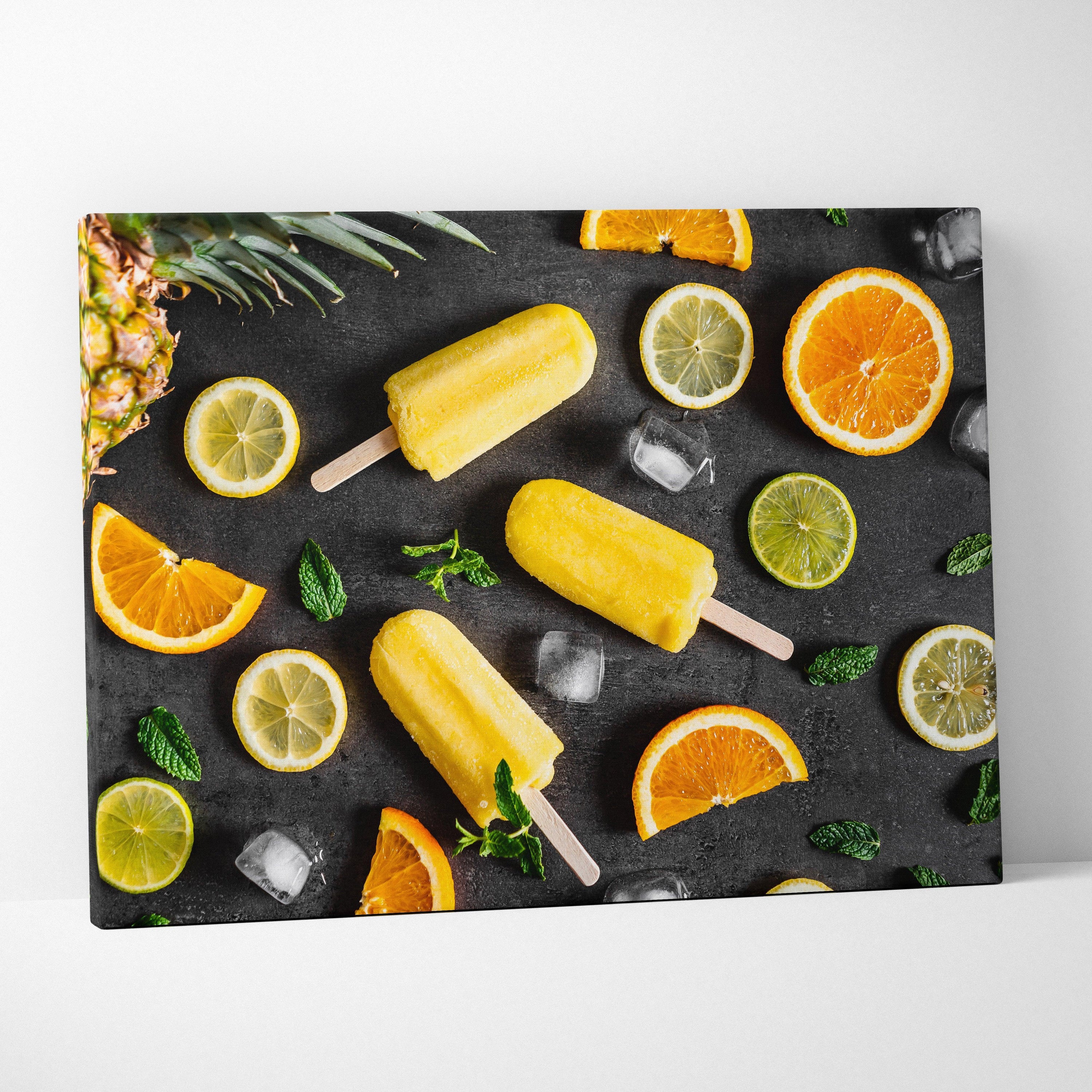 Canvas wall art featuring vibrant yellow popsicles, sliced oranges, limes, and mint leaves on a black background.