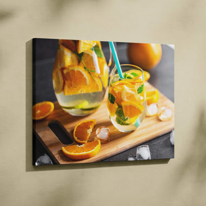 Canvas wall art featuring vibrant sliced oranges in a glass pitcher and mason jar with mint on a wooden board.