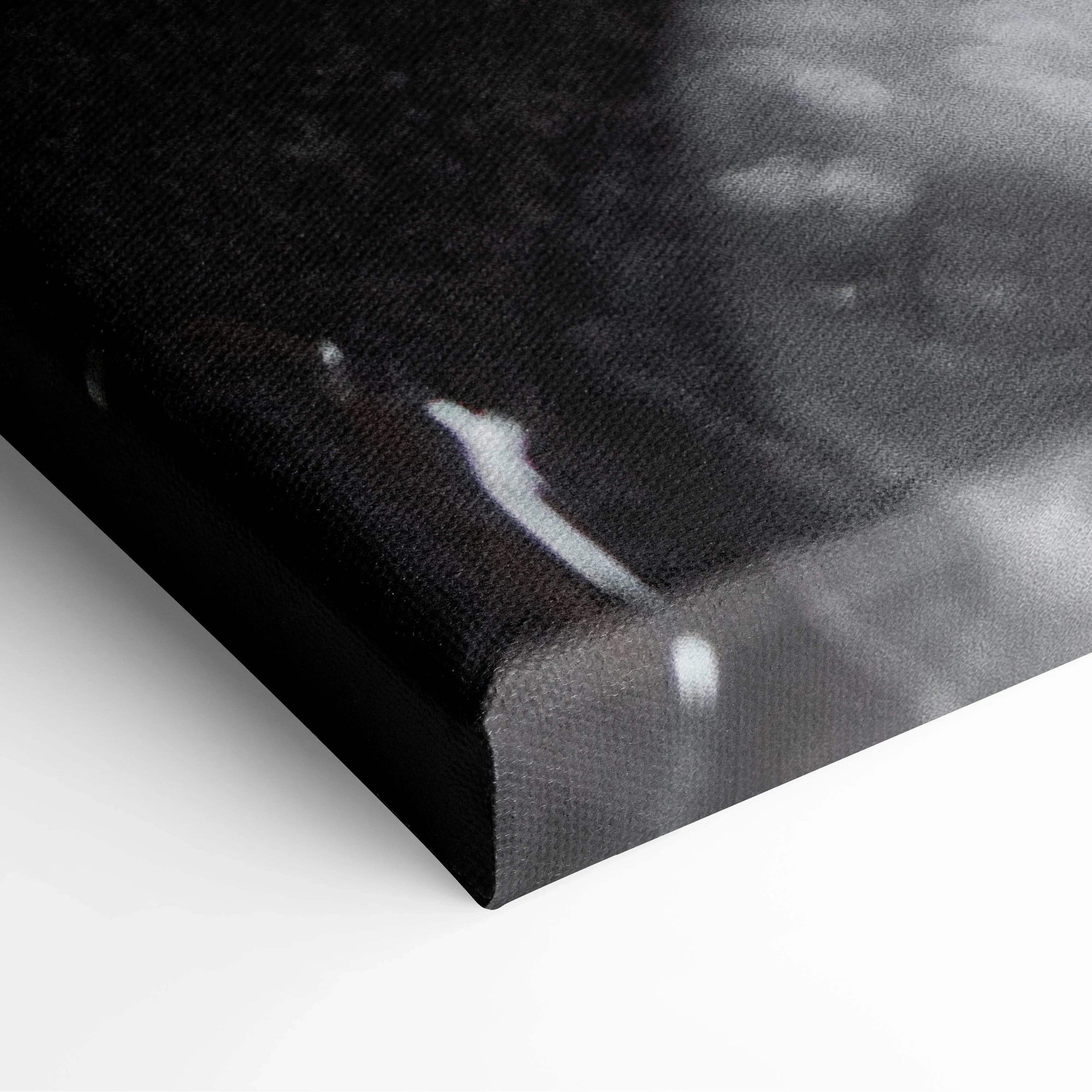 Close-up of black canvas wall art texture with subtle white highlights and wrapped edges.