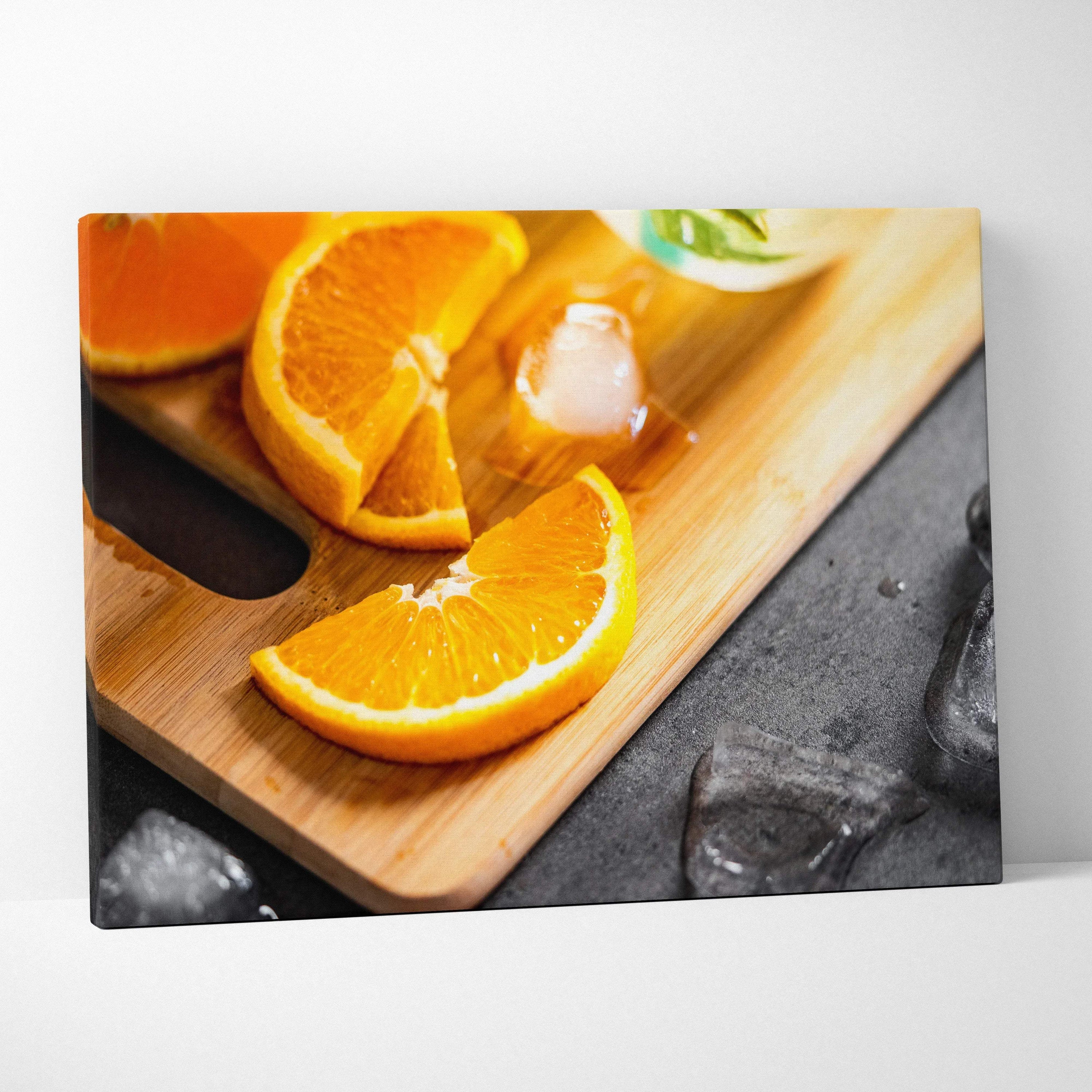Canvas wall art featuring vibrant sliced oranges on a wooden cutting board with ice cubes for fresh home decor.