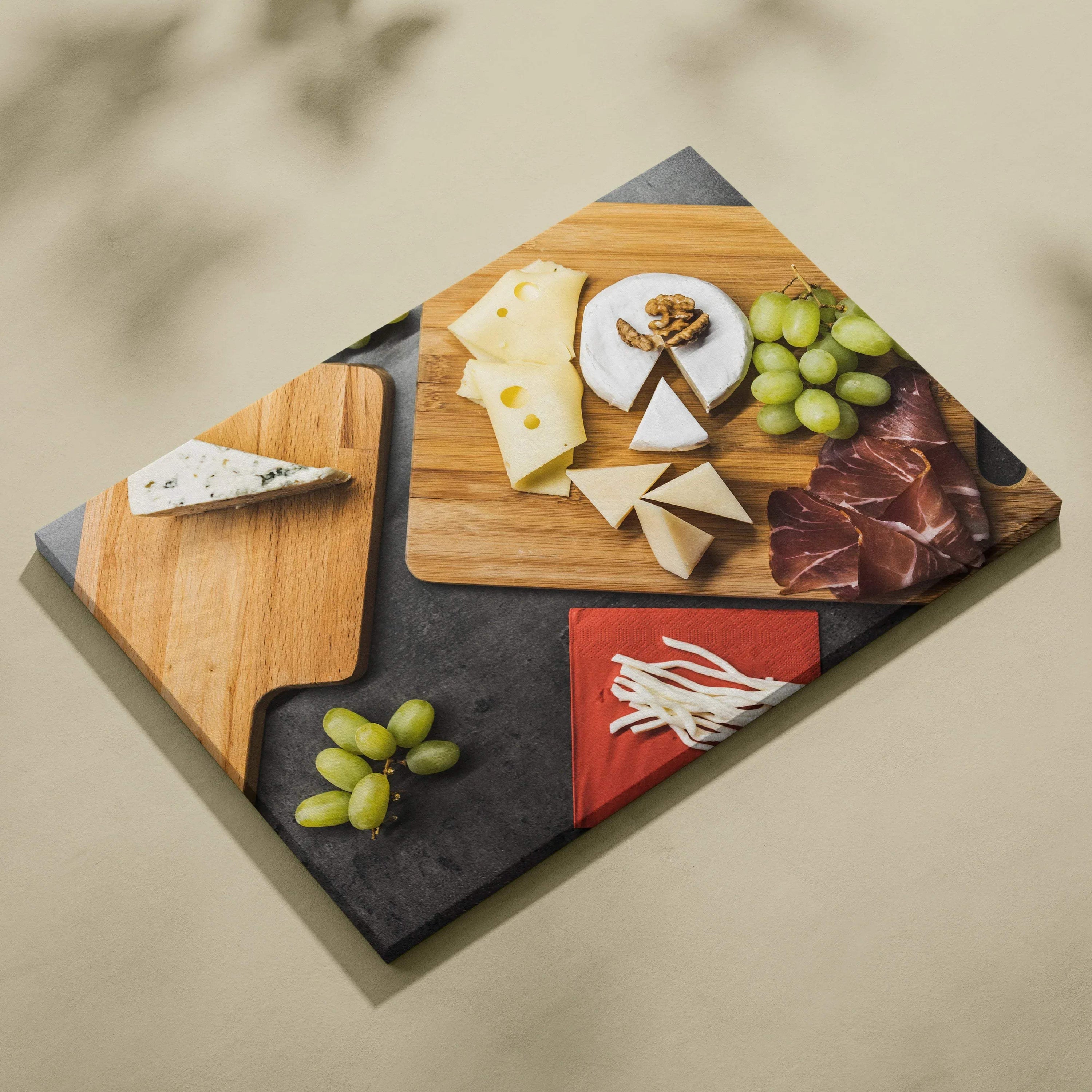 Canvas wall art featuring an overhead view of cheese varieties, grapes, cured meats, and fresh herbs on wooden cutting.