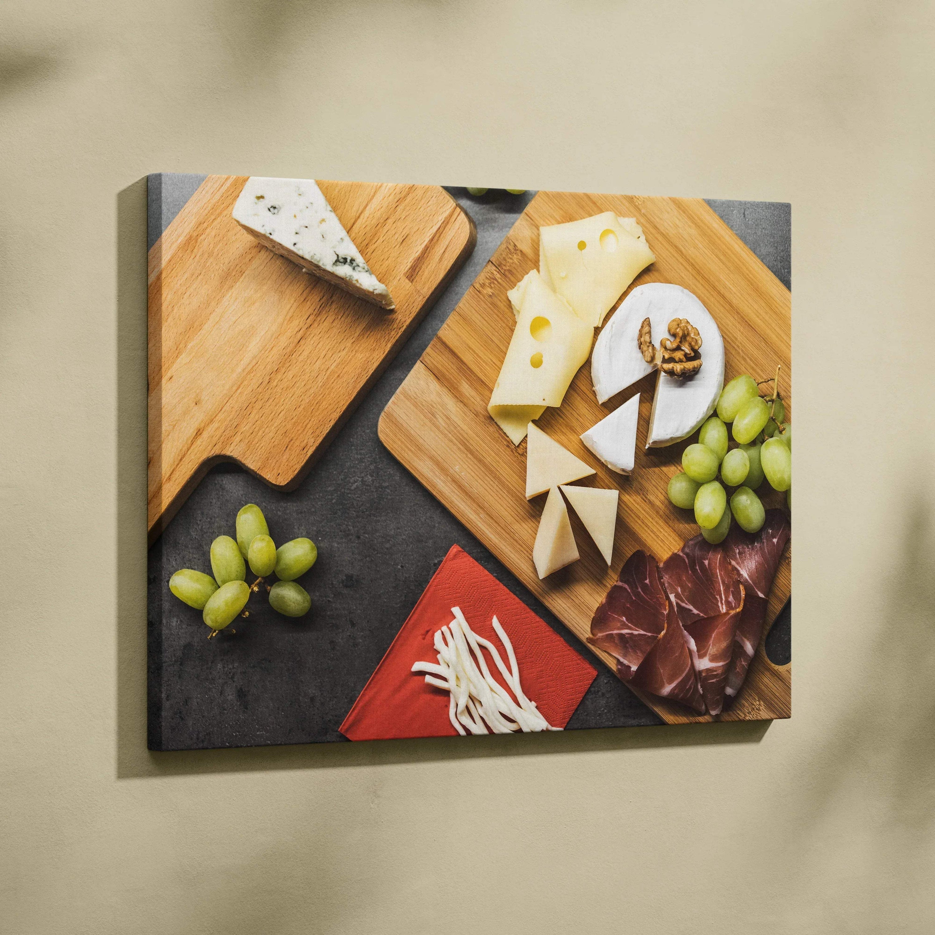 Canvas wall art featuring cheese wedges, round brie, grapes, cured meats, and nuts on wooden boards with a dark background.