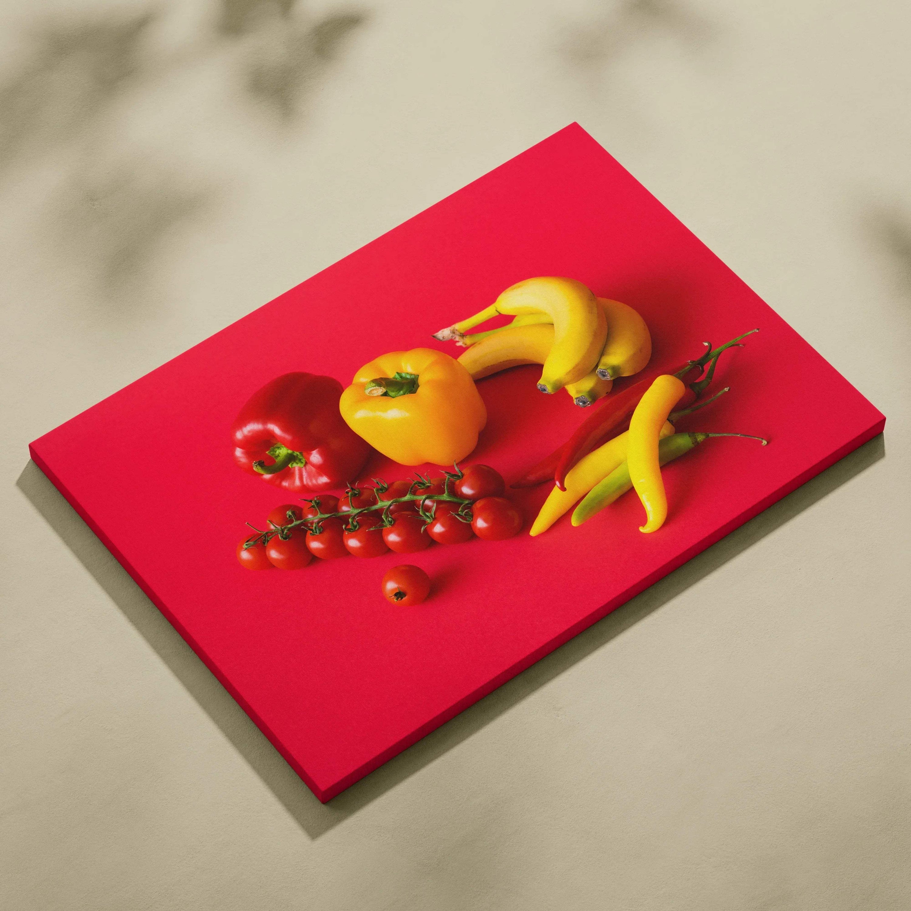 Vibrant canvas wall art featuring bananas, red and yellow peppers, cherry tomatoes on a bold red background decor.