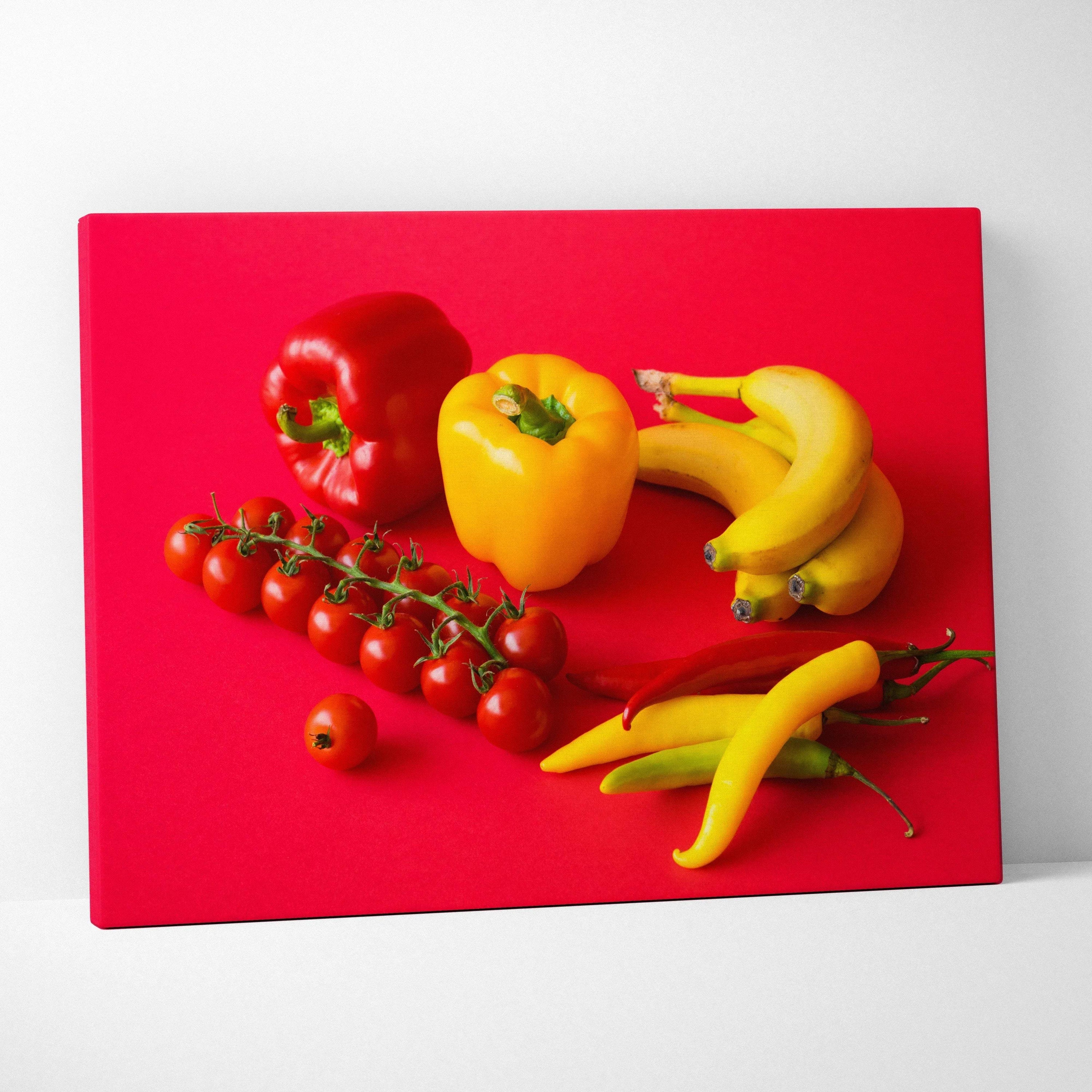 Vibrant canvas wall art featuring bananas, yellow and red peppers, and cherry tomatoes on red background decor.
