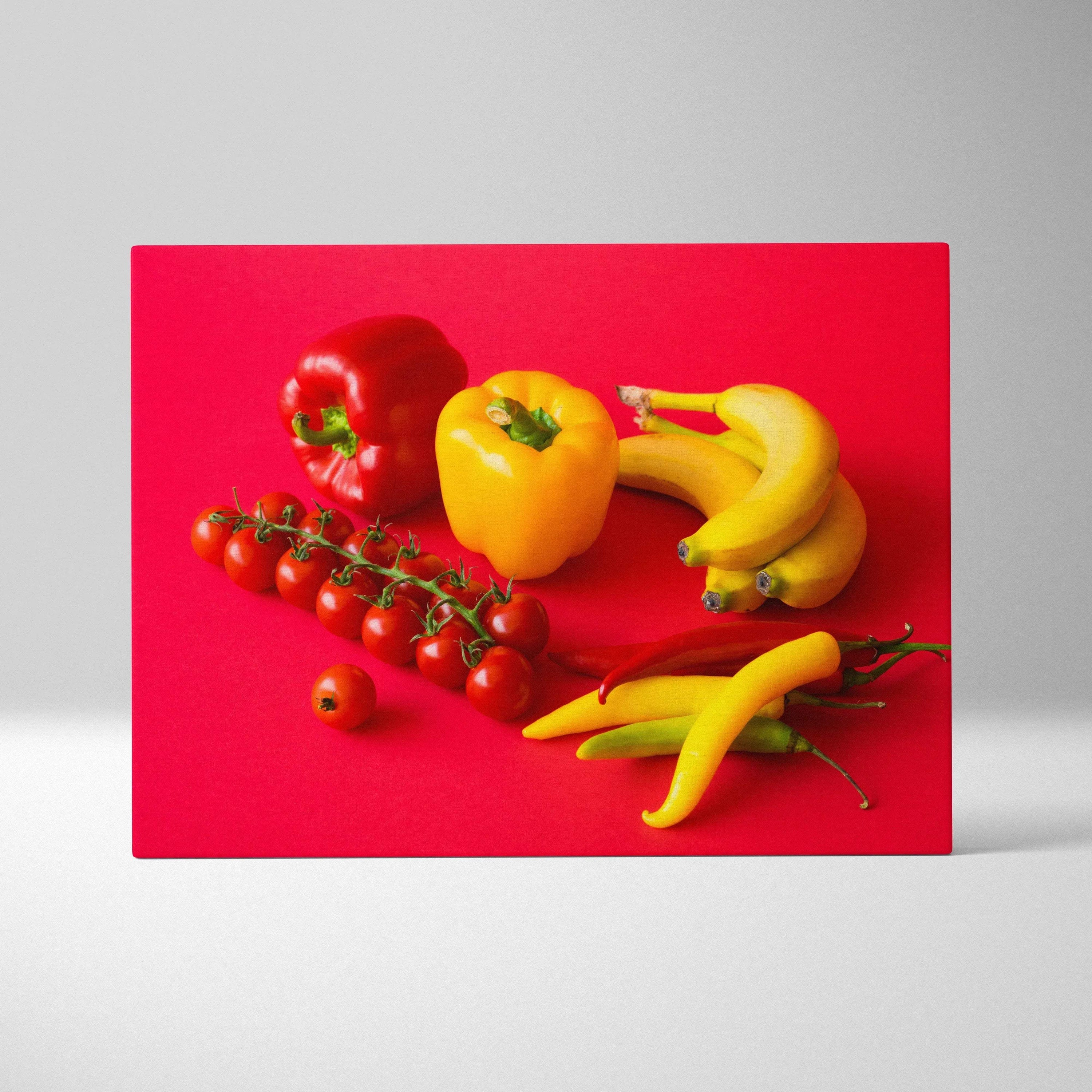 Canvas wall art featuring vibrant bananas, yellow pepper, cherry tomatoes, and red pepper on bright red background decor.