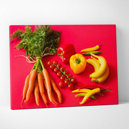 Colorful canvas wall art depicting fresh carrots, red and yellow bell peppers, bananas, and cherry tomatoes on a bright red.