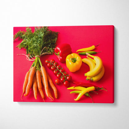 Vibrant canvas wall art featuring bananas, carrots, yellow and red peppers, and cherry tomatoes on a bold red background.