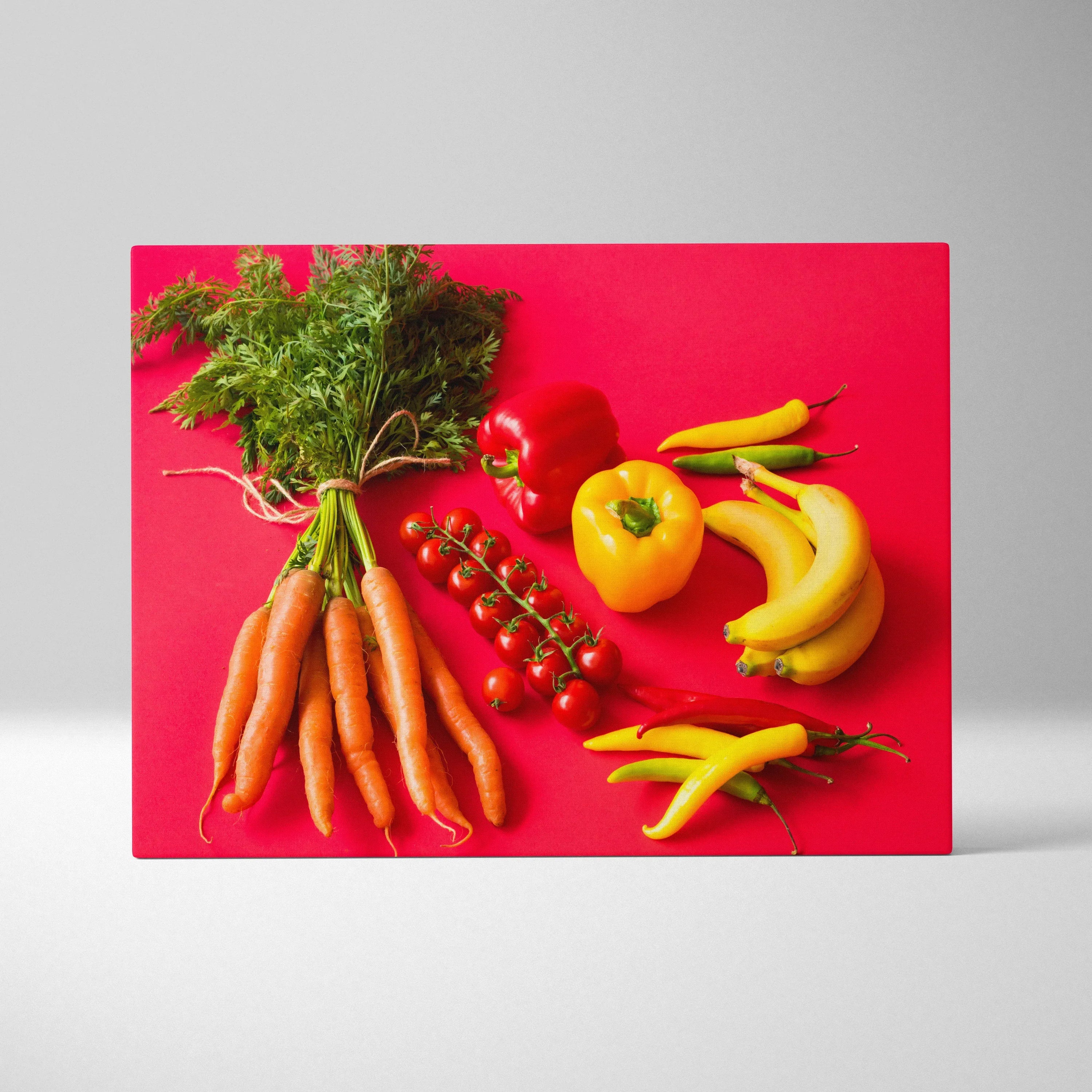 Colorful canvas wall art featuring bright carrots, bananas, yellow bell pepper, red peppers, and cherry tomatoes on a bold.