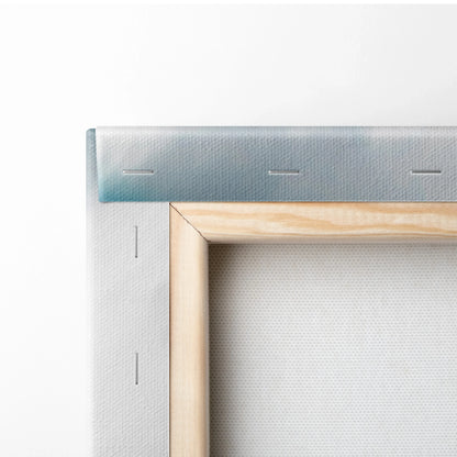 Close-up of wooden frame corner with white stretched canvas and metal staples securing fabric on back.