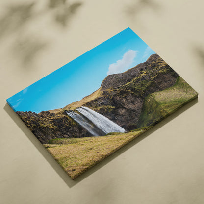 Canvas wall art featuring a vibrant Icelandic waterfall with rocky cliffs and bright blue sky.