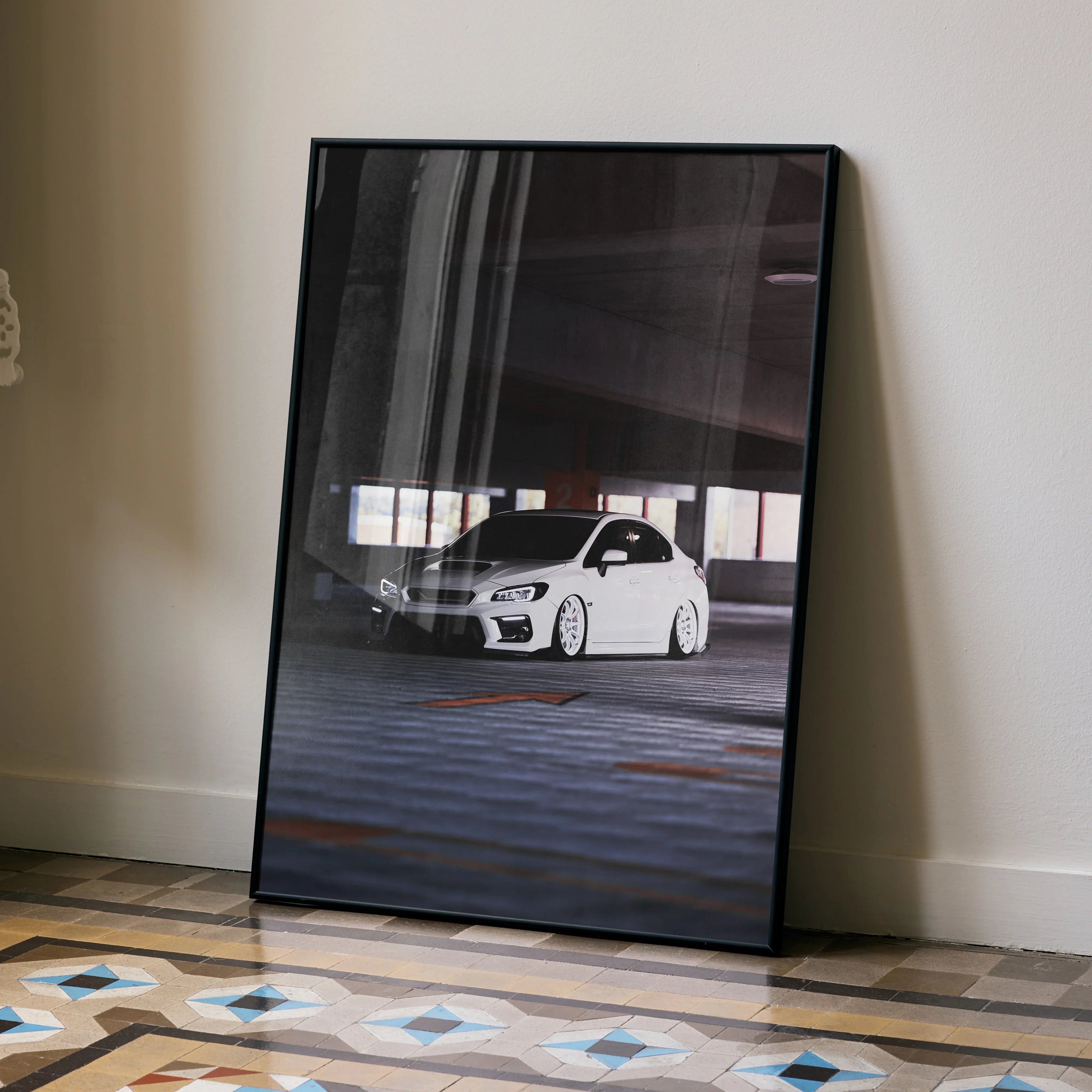 Subaru WRX white car poster in black frame leaning against wall, automotive wall art.