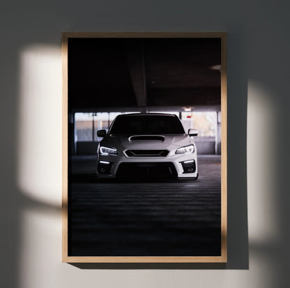 Subaru WRX front view poster in dark garage setting, framed wall art with moody lighting.