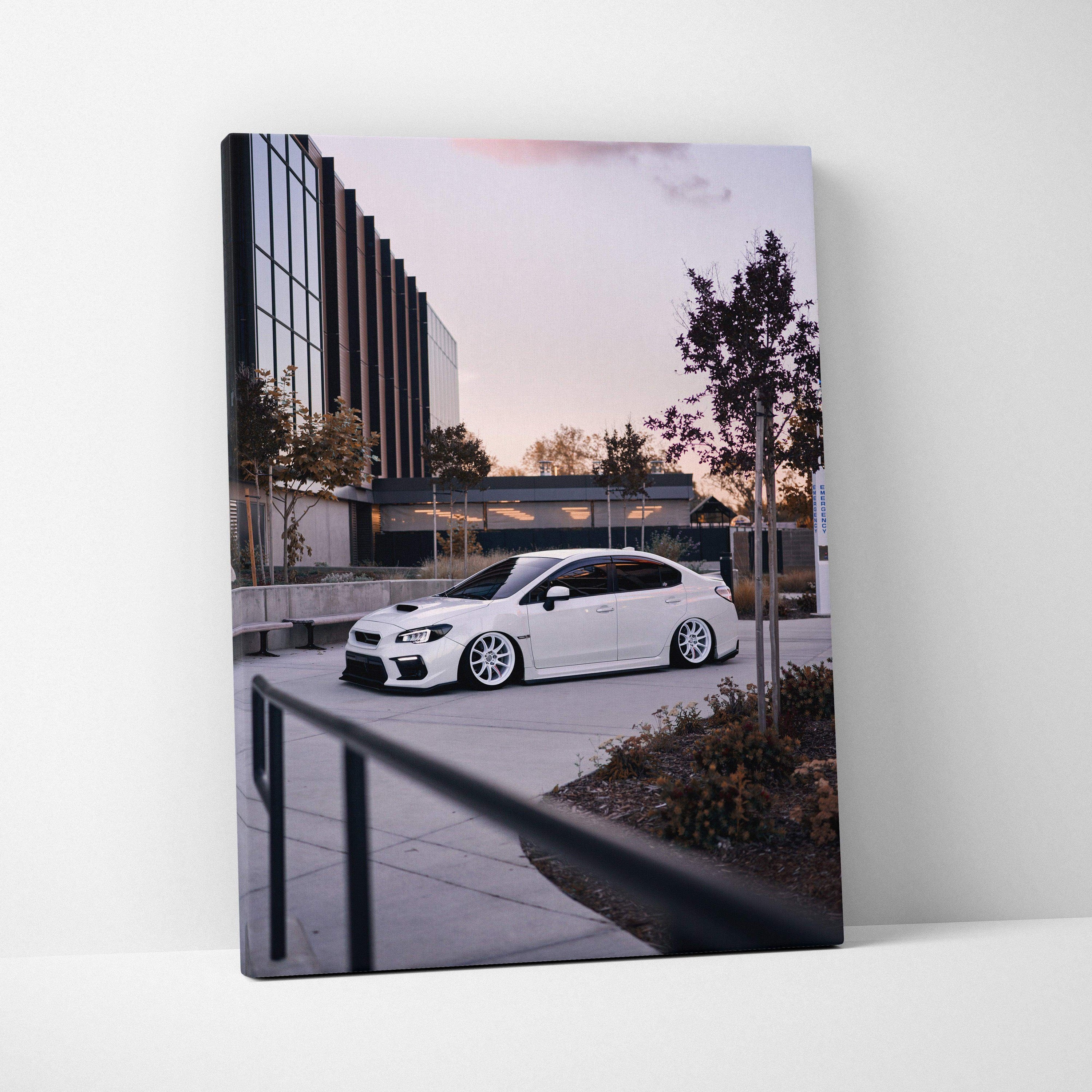 Vertical canvas art featuring a white Subaru WRX parked outside a modern building at dusk, wall art showcasing.