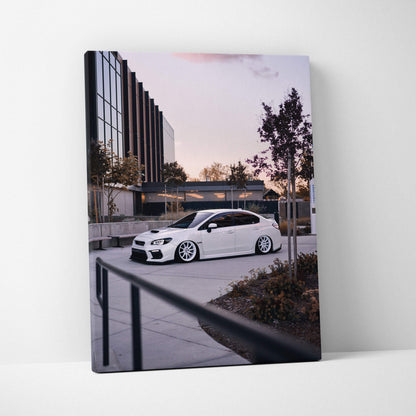 Vertical canvas art featuring a white Subaru WRX parked outside a modern building at dusk, wall art showcasing.