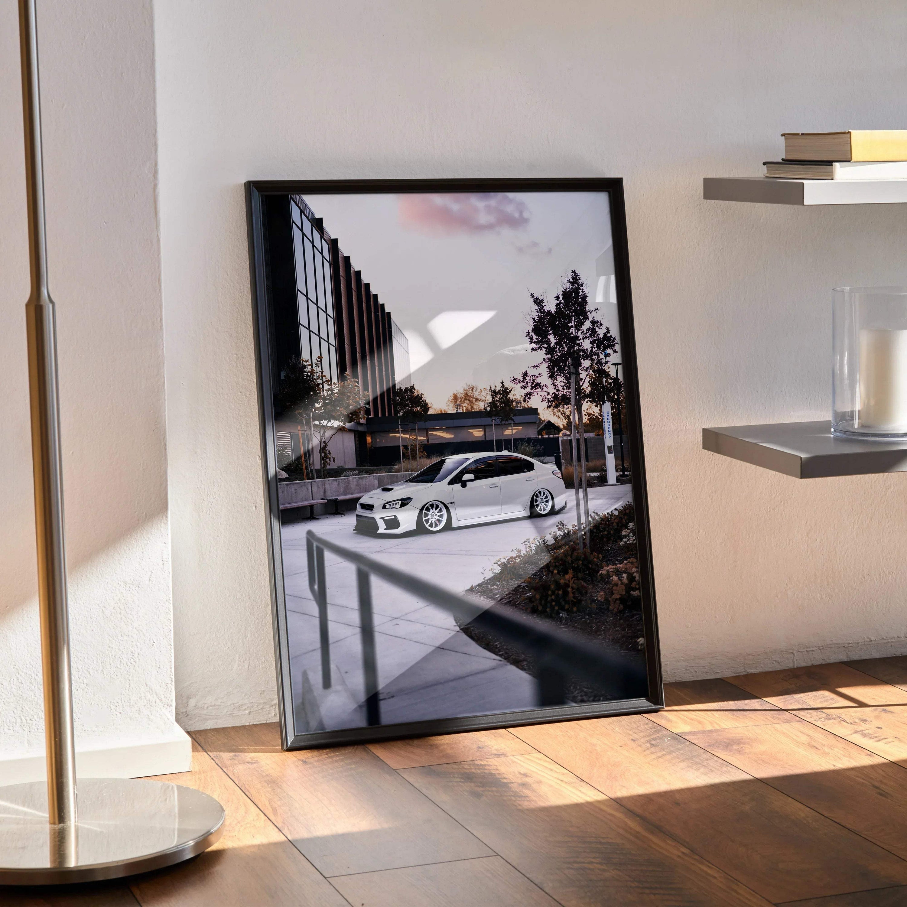 Subaru WRX white car poster wall art in black frame leaning against wall on wooden floor.