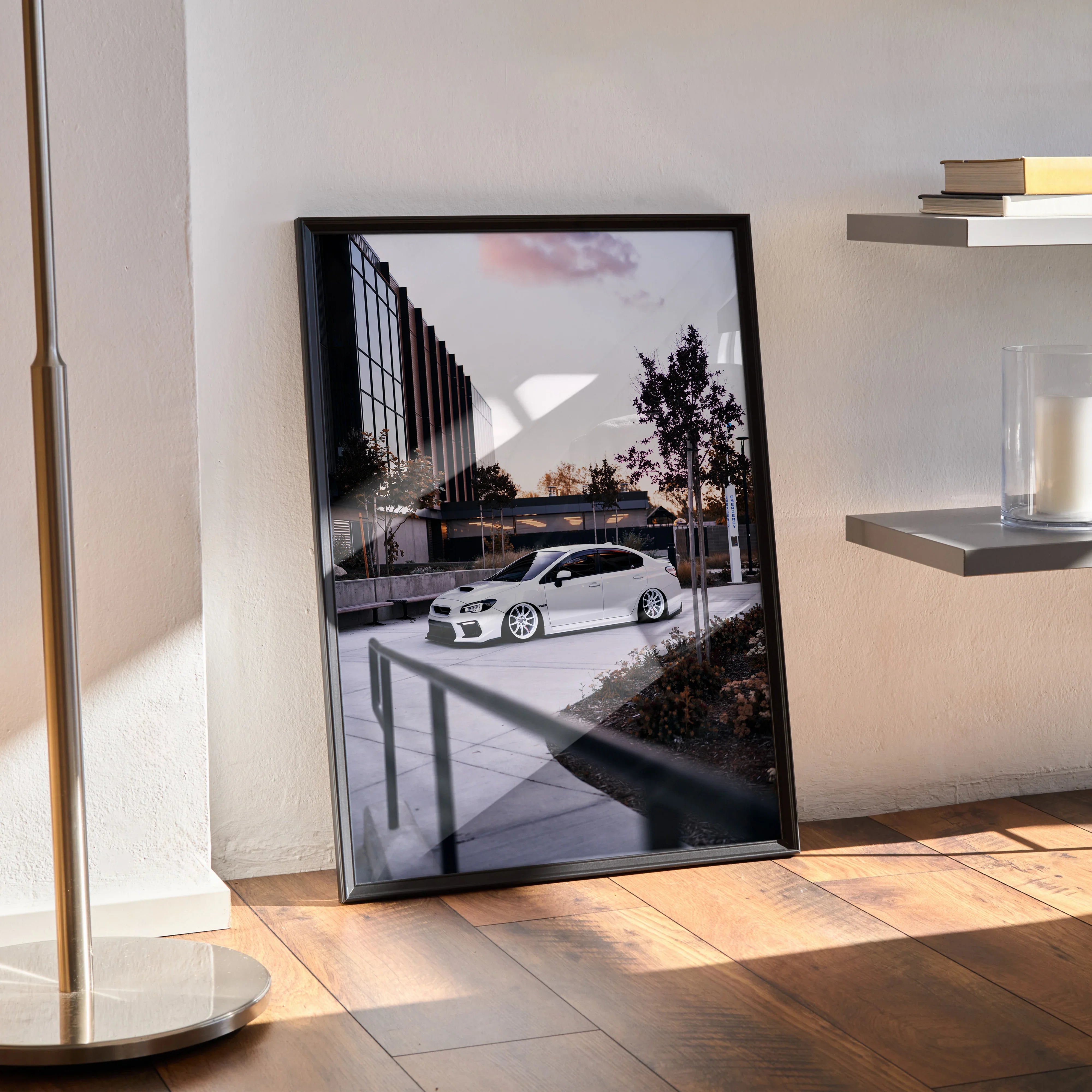 Subaru WRX white car poster wall art in black frame leaning against wall on wooden floor.
