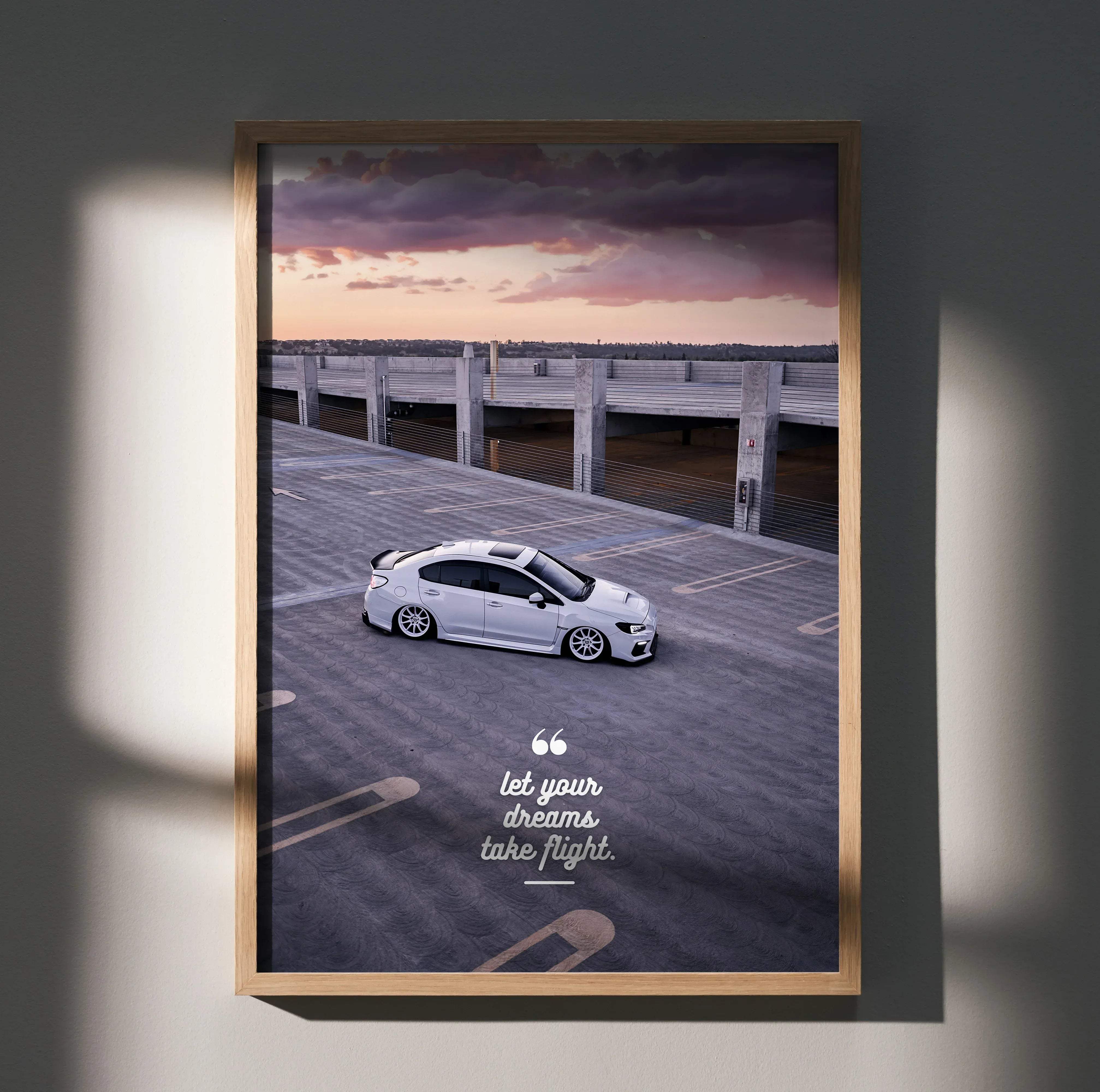 A framed motivational poster featuring a white Subaru WRX sports car and inspiring text let your dreams take flight
