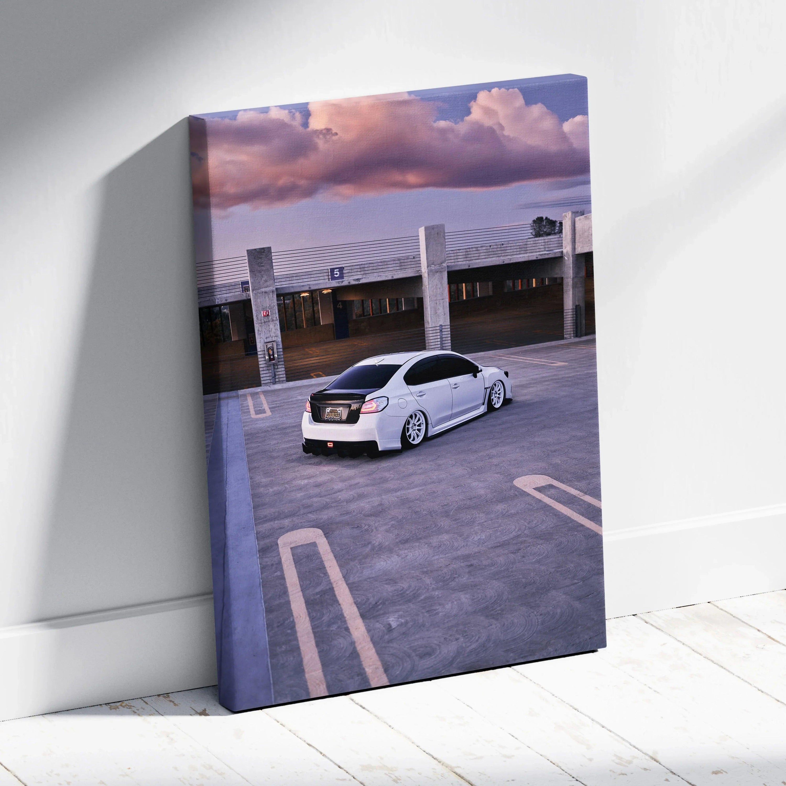 Vertical canvas wall art featuring a white Subaru WRX in an empty parking lot at sunset.