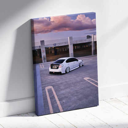 Vertical canvas wall art featuring a white Subaru WRX in an empty parking lot at sunset.