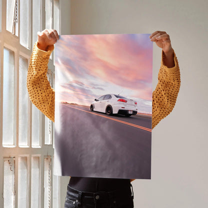 Mitsubishi Evo 10 driving on open road at sunset poster wall art in vibrant sky colors.