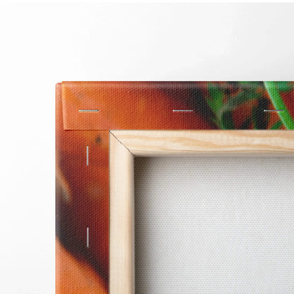 Close-up of a corner of canvas wall art with vibrant orange carrot colors and a natural wooden frame.