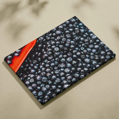 Canvas wall art featuring a close-up of vibrant, glossy blueberries with a splash of red in the corner.
