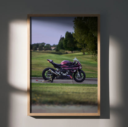 BMW S1000RR motorcycle poster wall art featuring a purple bike on a racetrack with green landscape background.