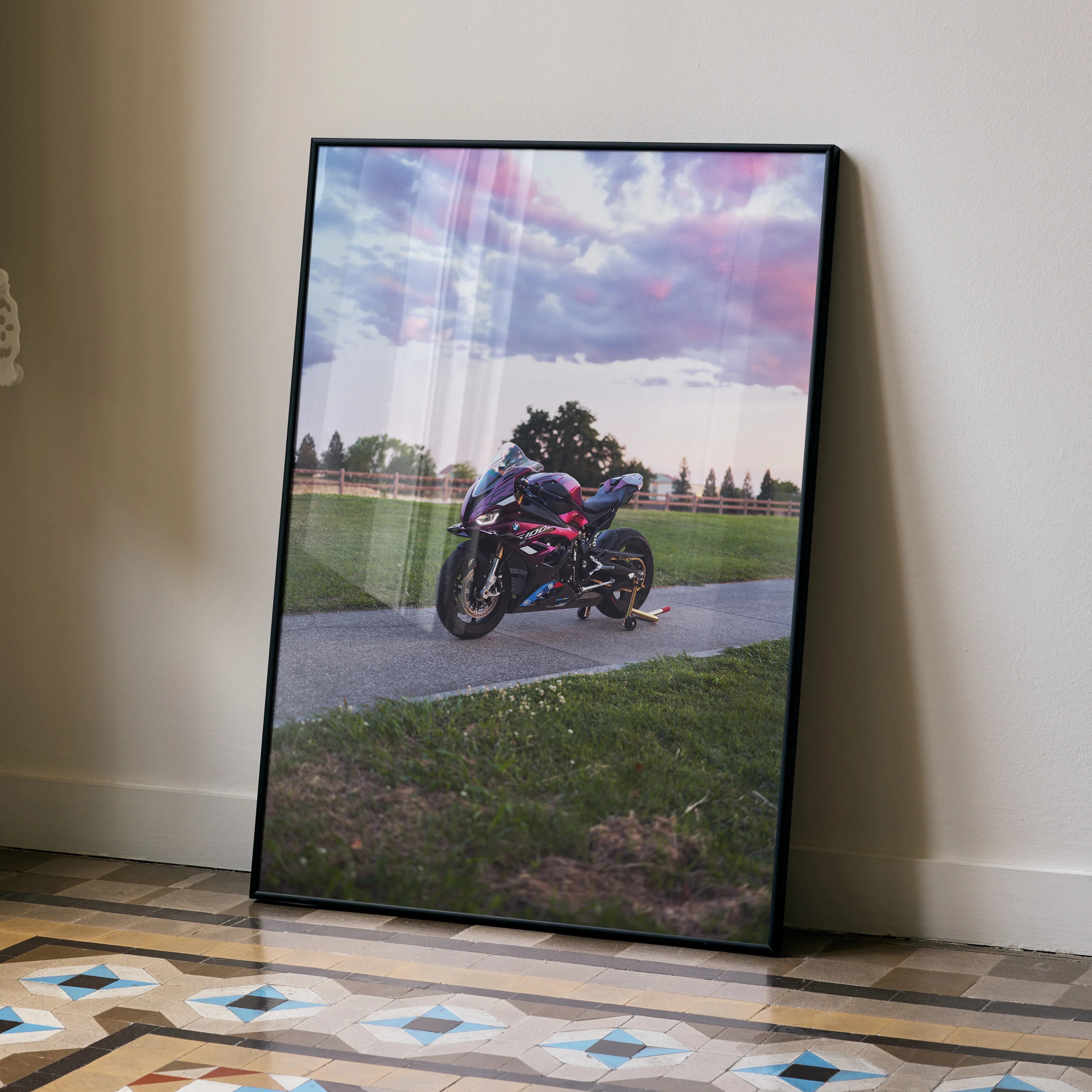 BMW S1000RR motorcycle poster with vibrant sunset sky, displayed as framed wall art on floor.
