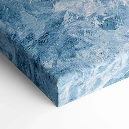 Abstract blue and white swirling colors on textured canvas wall art corner close-up.