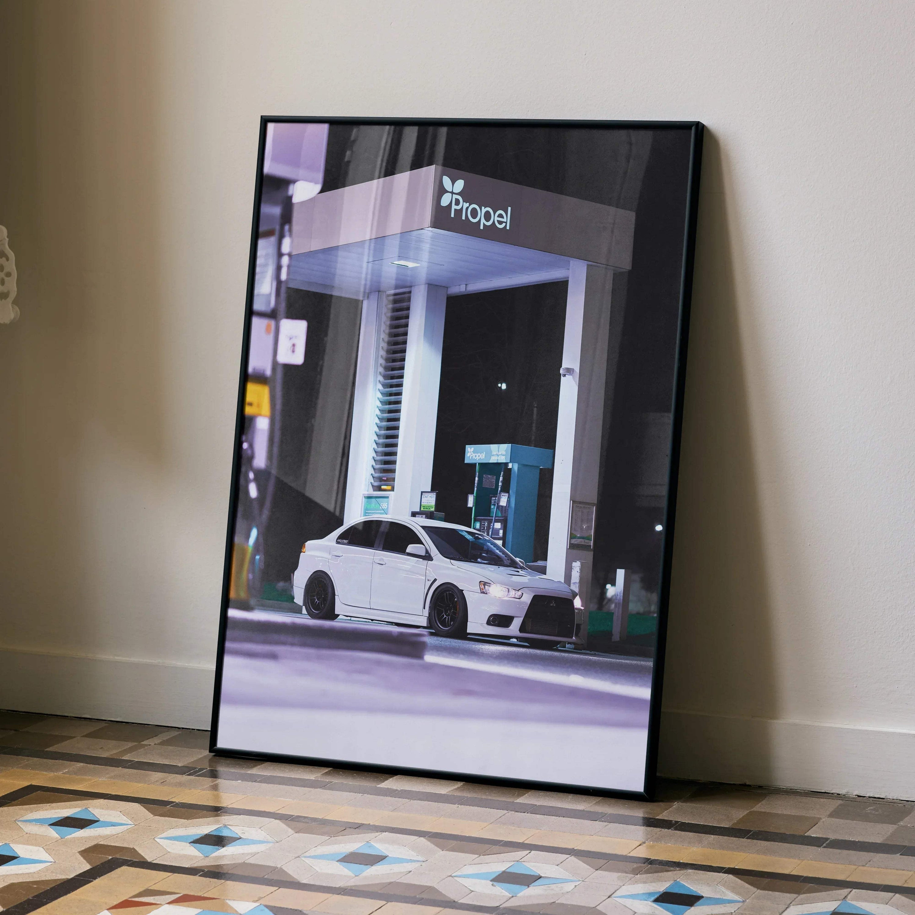 Mitsubishi Evo 10 poster with sleek white car at gas station, modern wall art on floor.