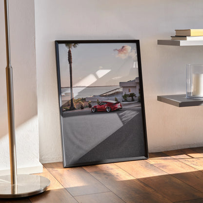 Nissan 370z poster wall art featuring a red sports car on a coastal road at sunset in a black frame.