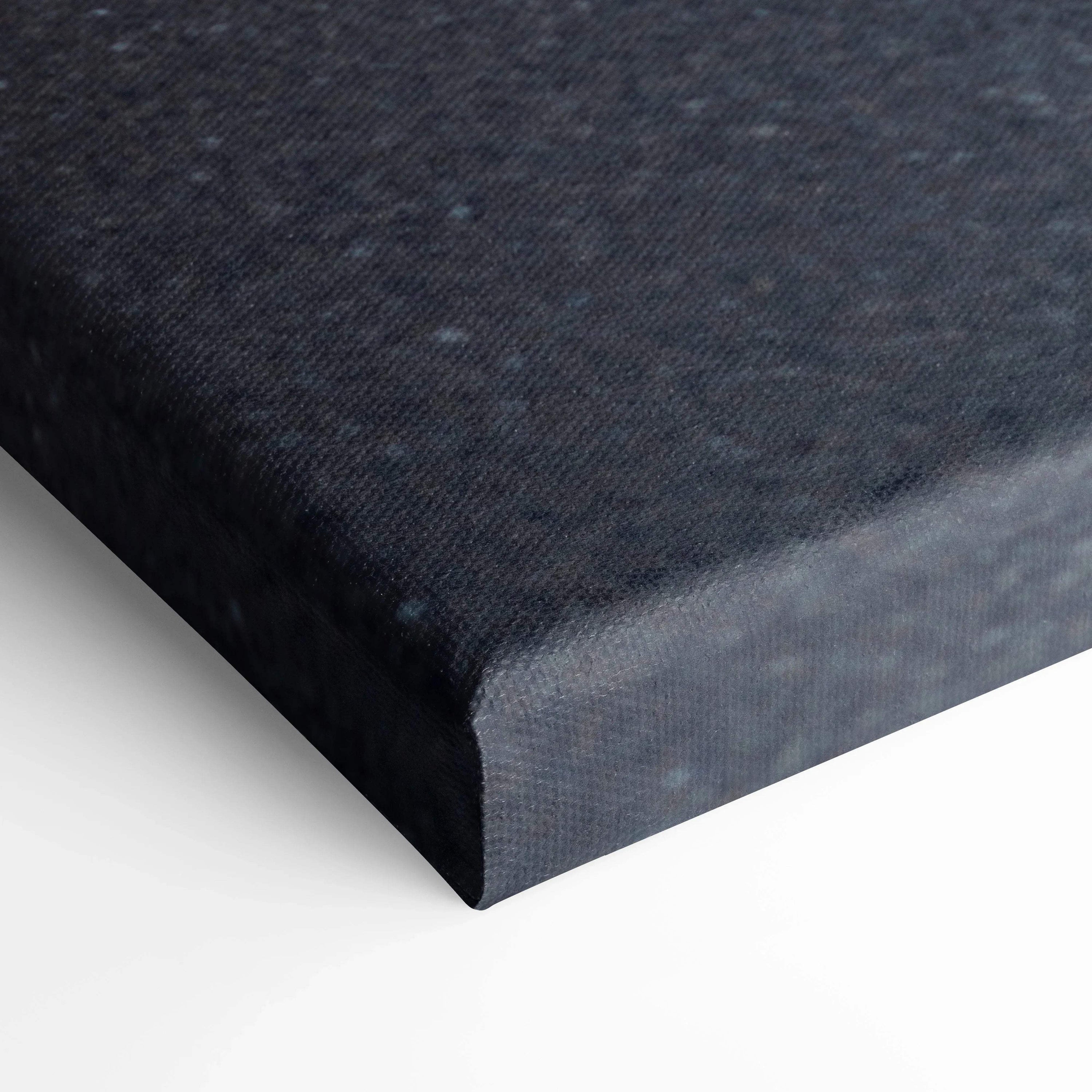 Close-up of edge of black canvas wall art with textured fabric surface and wrapped corners.