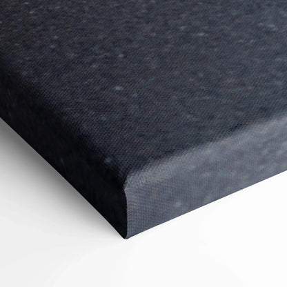 Close-up of edge of black canvas wall art with textured fabric surface and wrapped corners.