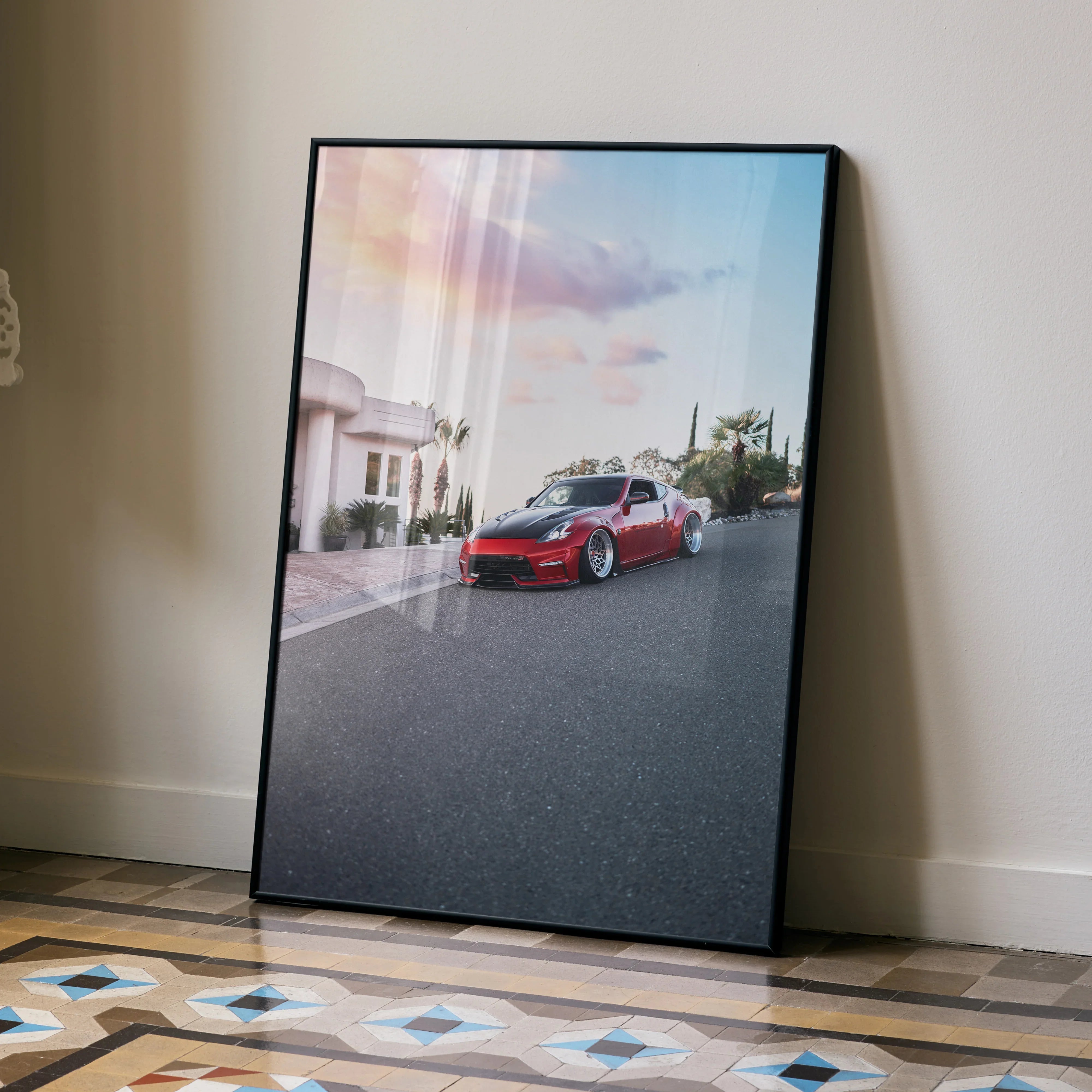 Nissan 370z poster with sunset backdrop displayed as modern wall art in black frame leaning against beige wall.