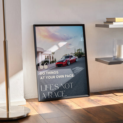 Motivational wall art poster featuring red Nissan 370z with inspiring text "Life's Not a Race" in sleek black frame.