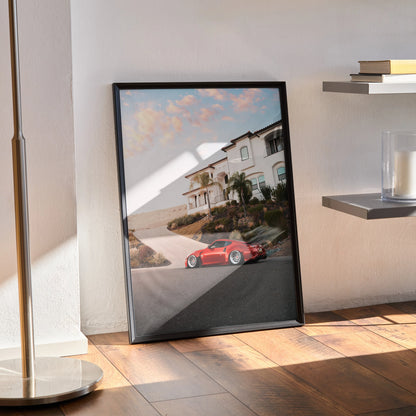Nissan 370z poster wall art with sunset and coastal road in black frame leaning on wooden floor.