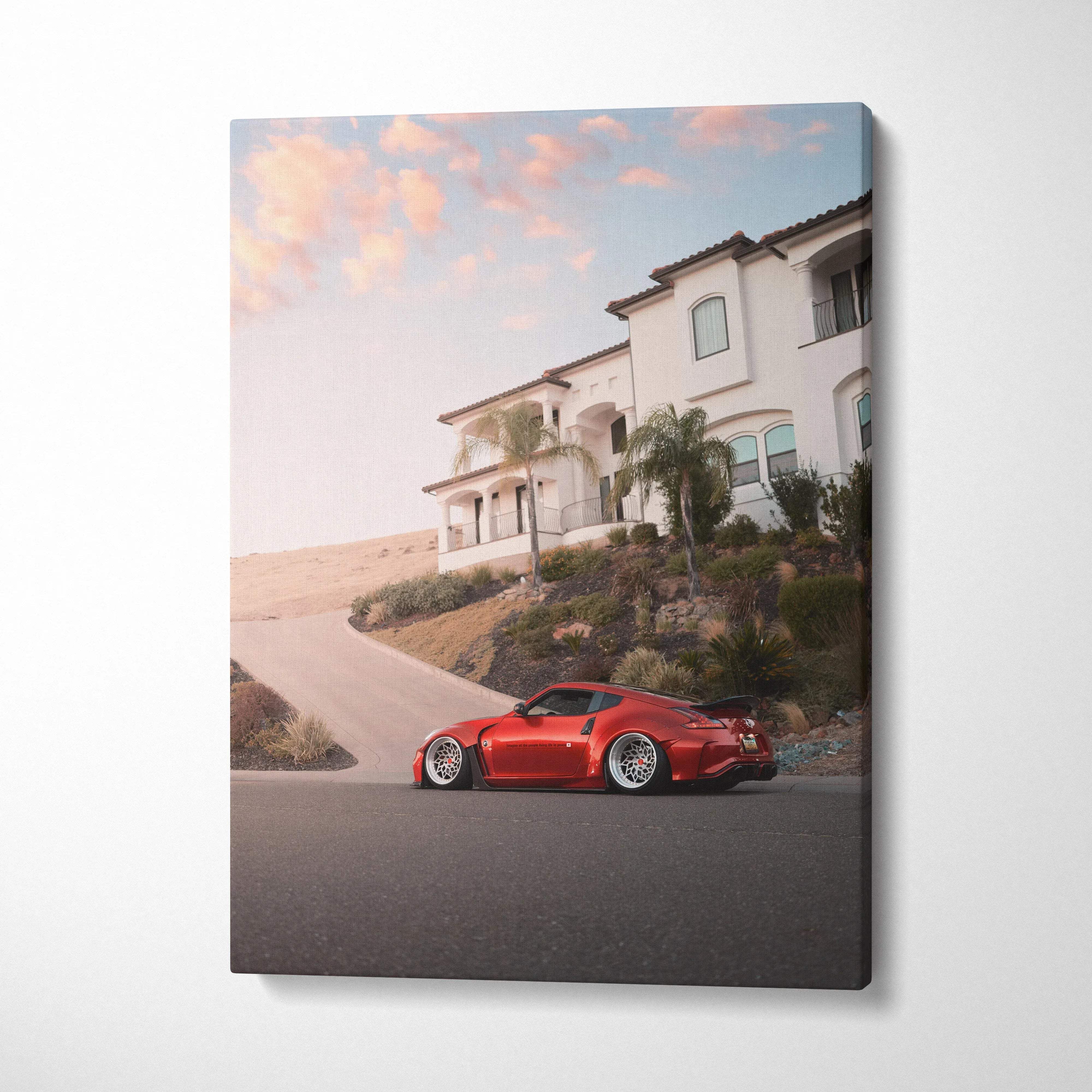 Red Nissan 370z parked near hillside house at sunset canvas wall art print.
