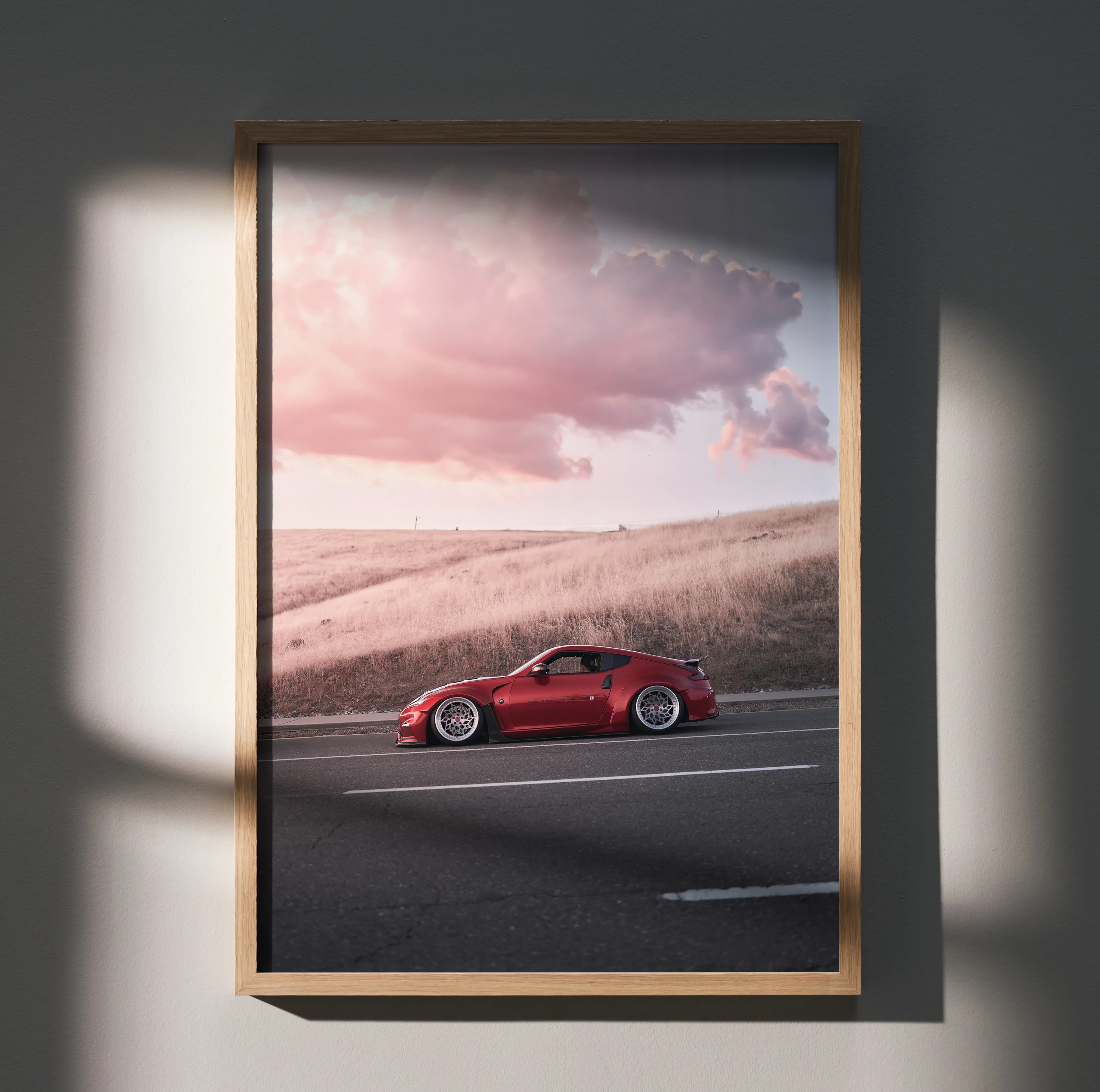 Nissan 370z red sports car driving on road at sunset poster wall art in wooden frame.