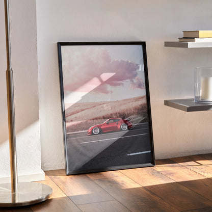 Nissan 370z poster with sunset backdrop in black frame leaning on wooden floor wall art.