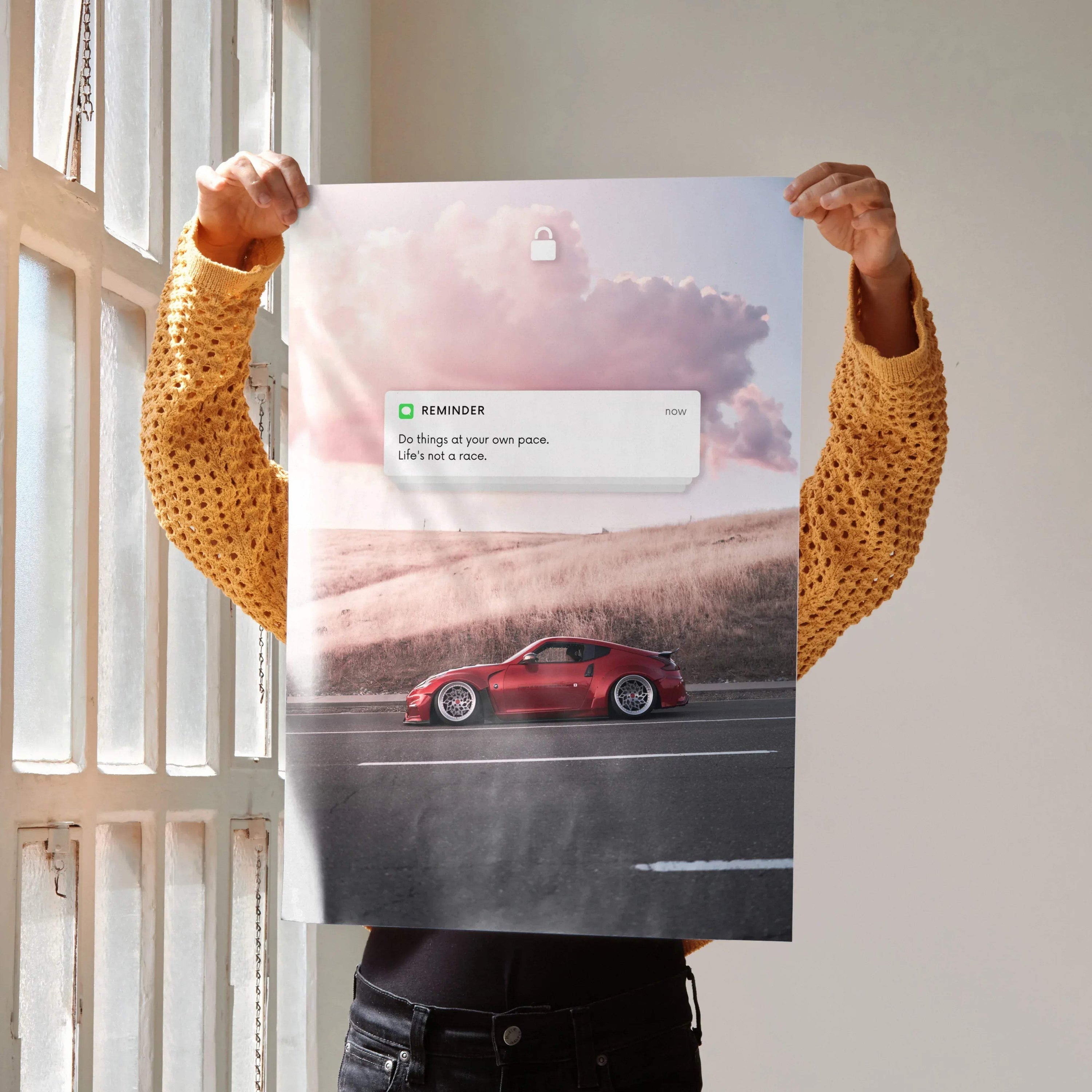 Motivational wall art poster featuring red Nissan 370z driving on road under pink cloudy sky.