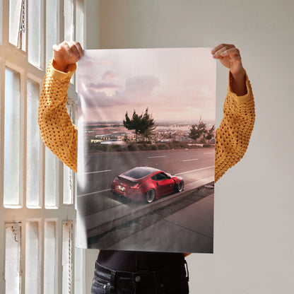 Nissan 370z driving at sunset with city skyline poster wall art in soft pink tones.