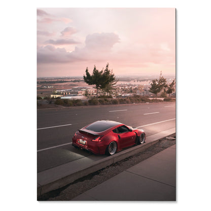 Red Nissan 370z parked by roadside at sunset with cityscape background poster wall art.