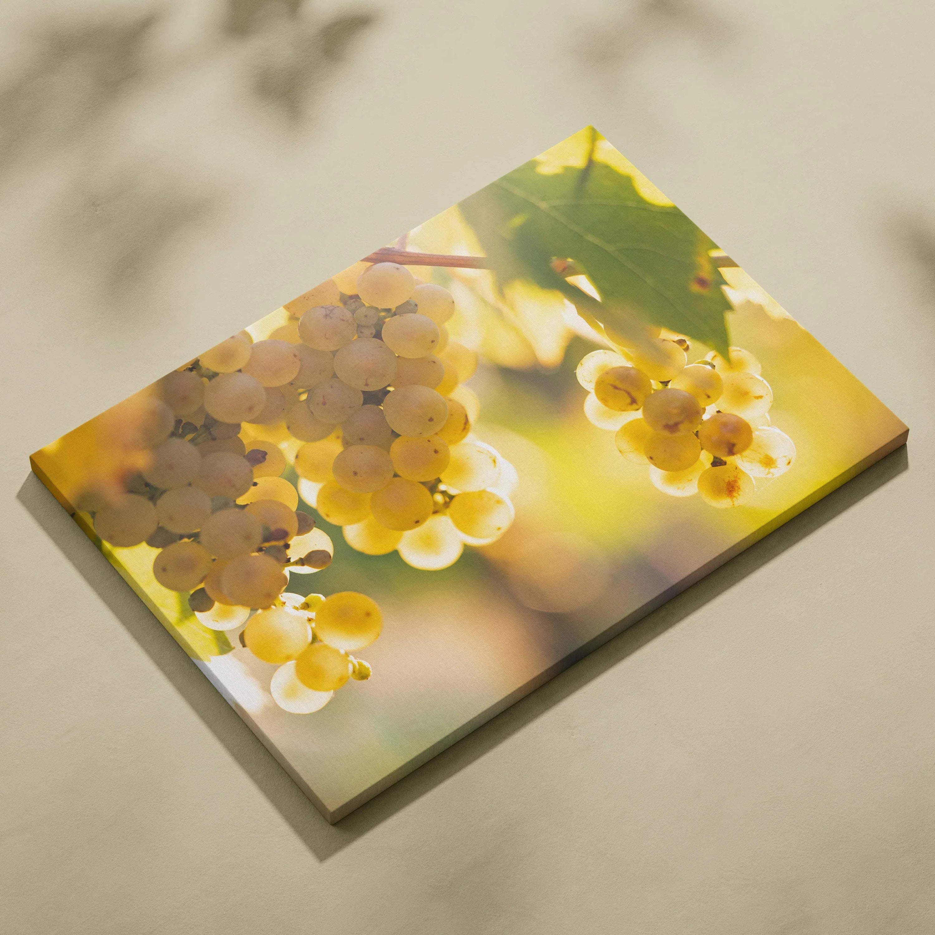 Canvas wall art featuring clusters of light green and yellow grapes with sunlit leaves against a blurred background.